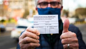 Senior man holding covid-19 vaccination record card